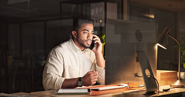 istock Businessman Working Late in Office Using Phone and Computer for Communication 2230913259
