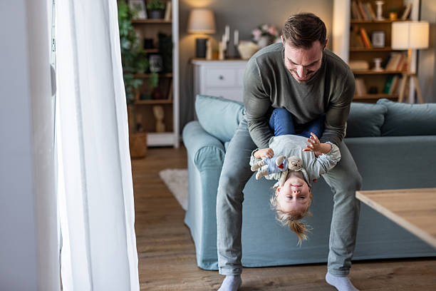 istock Father holding his daughter upside down, playing together at home 2230914509