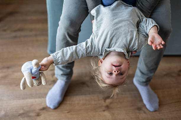 istock Father holding his upside down baby daughter playing at home 2230914523