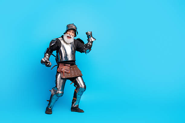 istock Energetic senior man dressed as a medieval knight posing on a vibrant blue background 2230915277