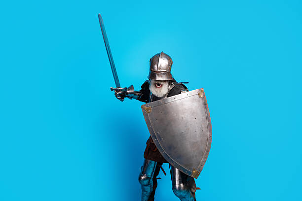 istock Medieval knight in full armor posing with sword and shield against a vibrant blue background exuding a bold and historical essence 2230915329