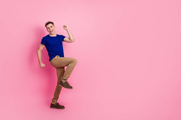 istock Cheerful young man joyfully celebrating with playful gestures on a bright pink background wearing casual fashion depicting excitement 2230915828