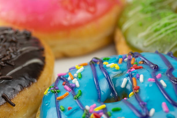 Detailed indoor studio stock image of assorted donuts, beautifully arranged to showcase a variety of flavors such as chocolate, strawberry, blueberry, and matcha green tea. The vibrant colors and textures highlight the delicious toppings, making this image perfect for food advertisements, bakery promotions, dessert menus, or lifestyle concepts related to sweet indulgence and snack enjoyment.
