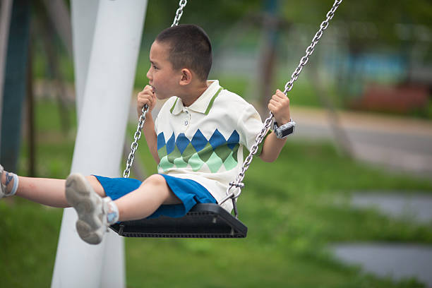 istock Little asian boy swinging on a swing. 2230916698