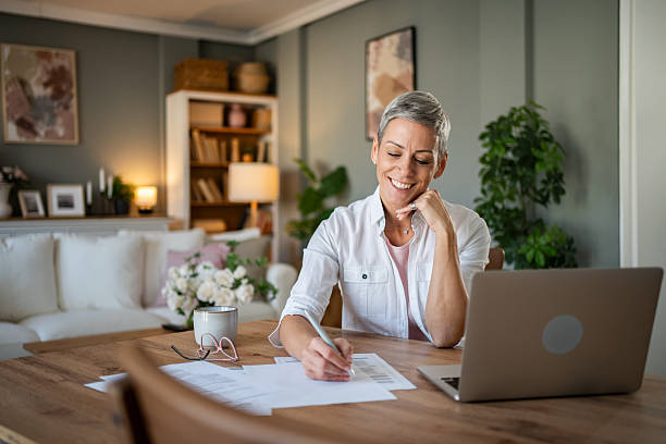 istock Smiling mature woman working from home office taking notes 2230917640