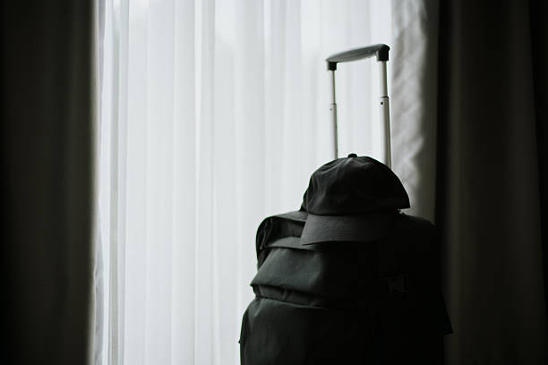 Travel suitcase with cap by the window getting ready to leave.