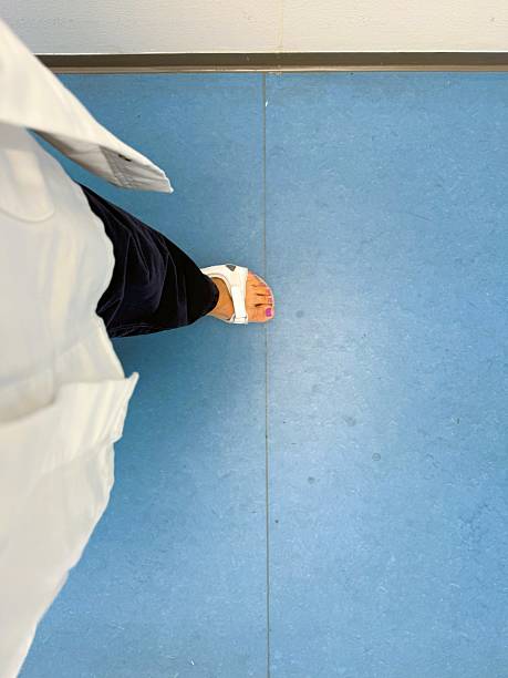 Close-up of a female physician’s legs walking through a bright Danish hospital corridor, dressed in medical uniform and sandals. Modern healthcare concept illustrating medical staff, professionalism, and everyday life in a clinical environmen