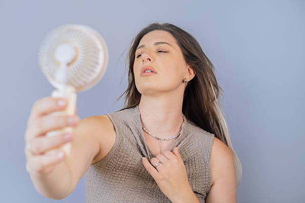istock Tired young woman using a lightweight mini gadget for instant cooling outdoors on a warm sunny day. 2230925169