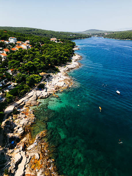 Scenic aerial view of rocky coastline with turquoise clear Adriatic Sea and houses by the shore.