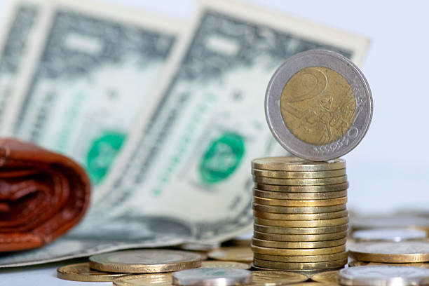 Stack of euro coins with US dollar banknote, symbolizing currency exchange, forex trading, savings, and international finance. Useful for topics of banking, economy, and global money markets.