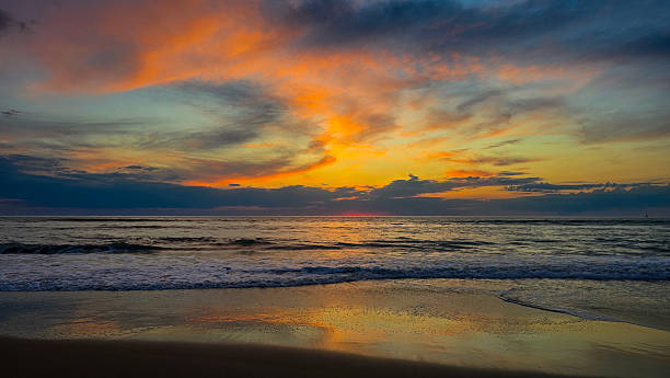 istock Romantic evening at sea or ocean beach during sunset or sunrise. The sunlight is reflected on the surface of water, orange clouds and wet sand. 2230935962