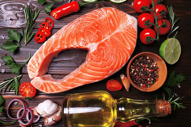 istock Salmon fish steak on wood background with spices and vegetables 2230936321