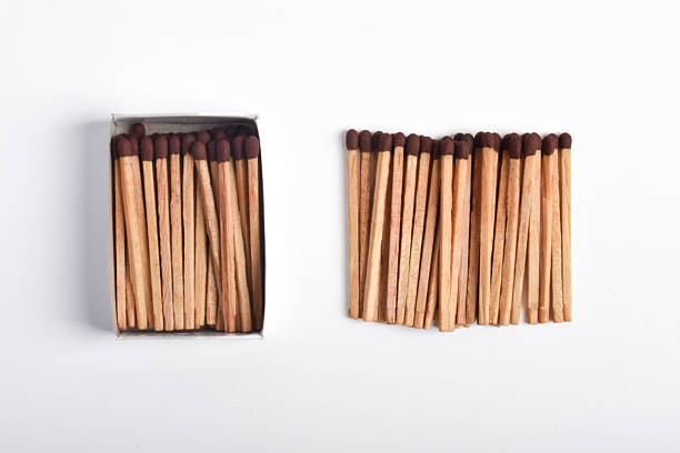 Multicolored matches lying in a box and on a paper background, in black and blue colors. Blue, yellow, and red matches illuminated by red light. Close-up.
