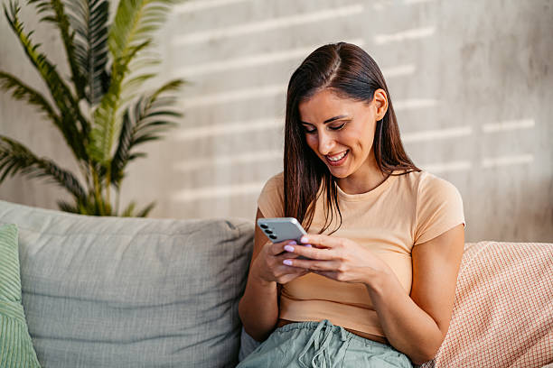 istock Young Woman Texting On The Phone While Sitting On The Sofa At Home 2230944639