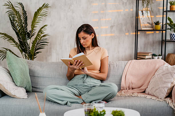 istock Young Woman Reading A Book At Home 2230944795