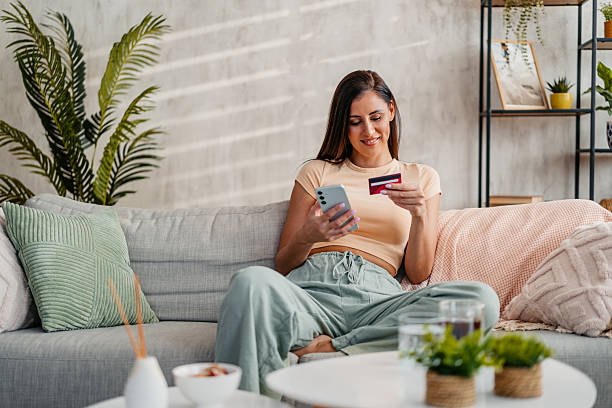 istock Young Woman Shopping Online At Home Using Phone 2230944832