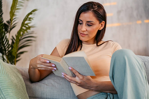 istock Young Woman Reading A Book At Home 2230944908