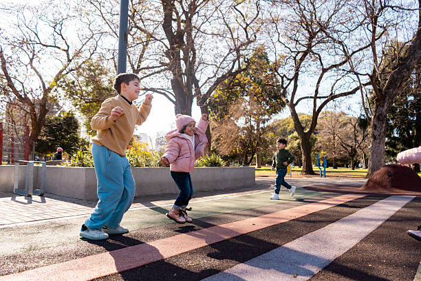 A family engages in fun outdoor activities, with children playing and exploring, creating a lively atmosphere during an excursion in a beautiful park surrounded by nature.