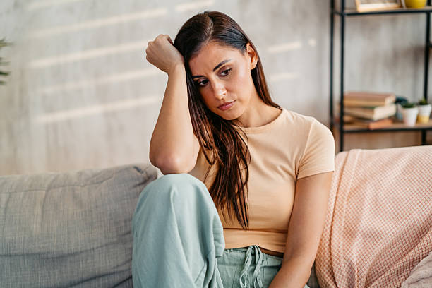 istock Sad Young Woman Sitting At Home On The Sofa 2230945718
