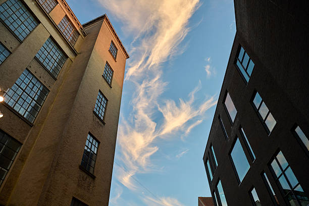 Cloudscape seen from street while looking up between tall industrial buildings