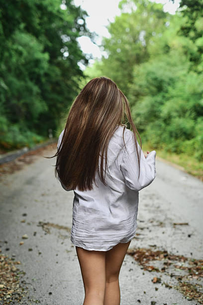 istock Long Haired Female Running Down Forest Road In White Shirt 2230951040