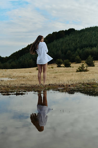Thoughtful Female Enjoying Peaceful Moment In Nature By Water Reflection