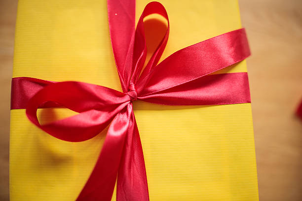 A gift wrapped in light-colored paper on a light green background, creating a minimal and festive composition. Copy space