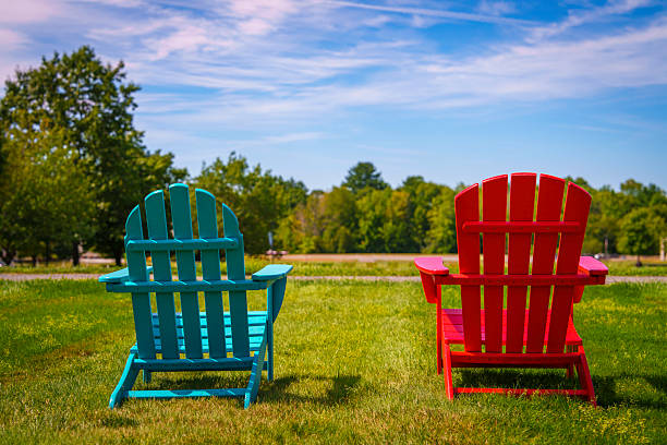 Two Adirondack chairsone red, one greensit side by side on a green lawn, offering a vibrant and peaceful setting for rest, reflection, and quiet conversation in the open air.