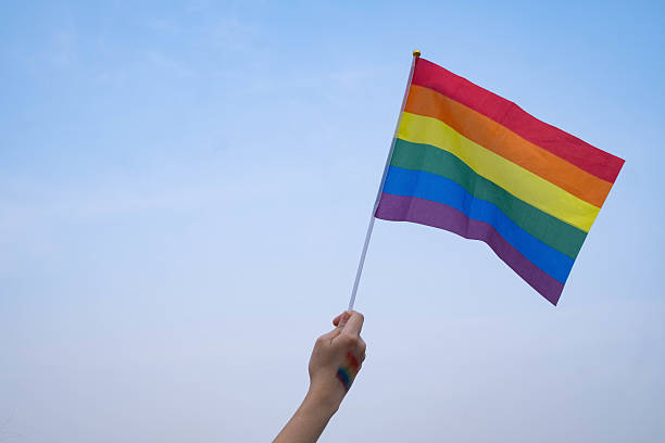 istock A hand waving a vibrant rainbow flag against a blue sky, symbolizing pride, diversity, and inclusivity. Perfect for celebrations and culture themes. 2230958202