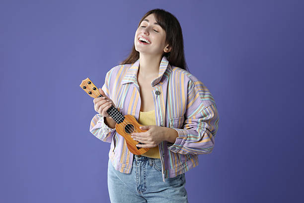 istock Happy woman playing ukulele on purple background, space for text 2230958543