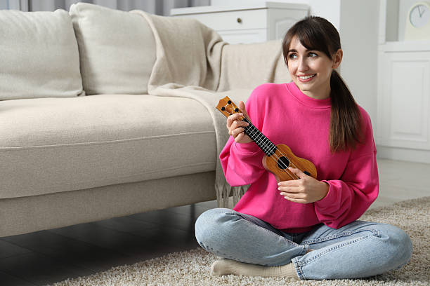 istock Happy woman playing ukulele on floor at home 2230958593