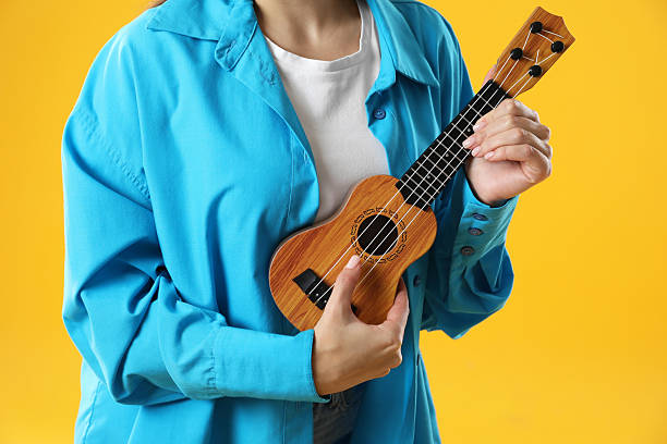 istock Woman playing ukulele on orange background, closeup 2230958629