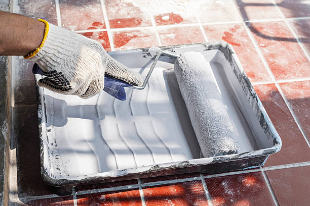 istock Construction worker in gloves using a paint roller to apply paint to a wall during home renovation. Home renovation project 2230958905