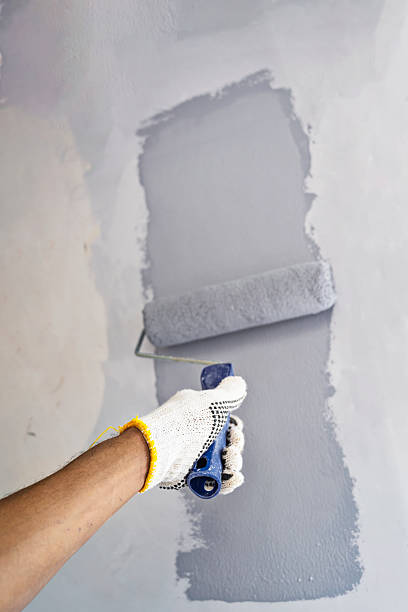 istock Construction worker in gloves using a paint roller to apply paint to a wall during home renovation. Home renovation project 2230958935