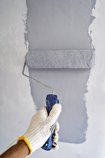 istock Construction worker in gloves using a paint roller to apply paint to a wall during home renovation. Home renovation project 2230958959