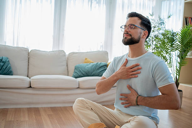 istock Young adult man practicing deep breathing exercise at home 2230960076