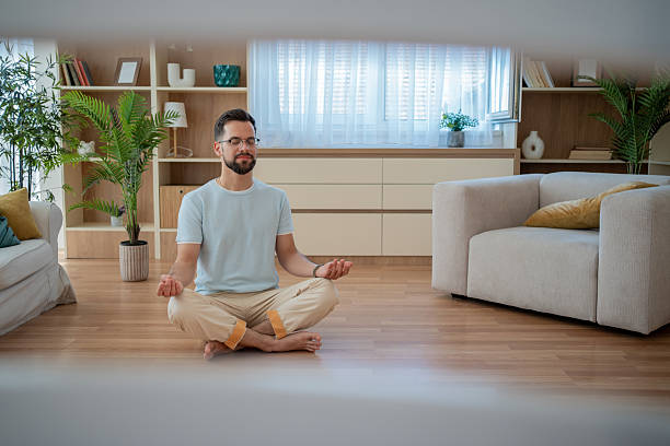 istock Young man meditating in the living room at home 2230960121