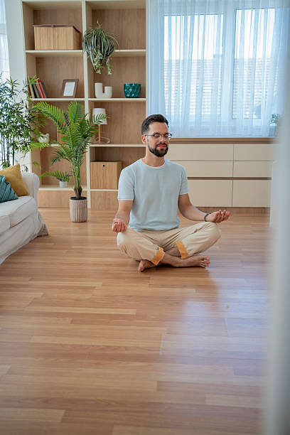 istock Young man meditating in the lotus position at home 2230960129