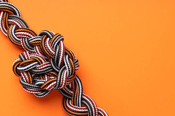 istock Colorful ropes tied in knot on orange background, top view and space for text. Unity concept 2230962093
