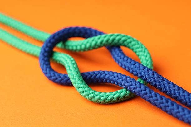 istock Colorful ropes tied in knot on orange background, closeup. Unity concept 2230962137