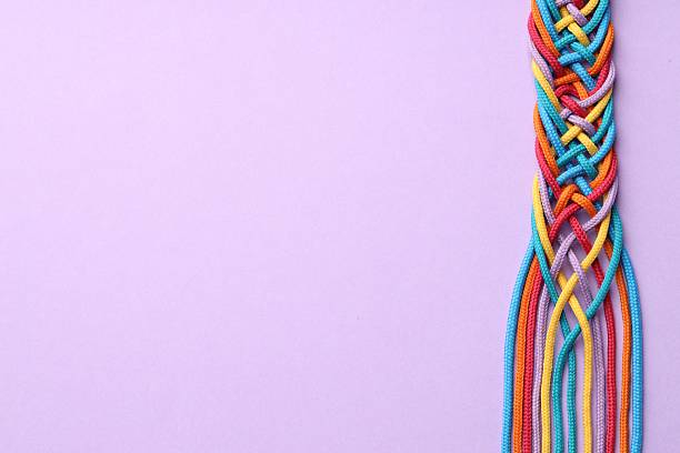 Colorful ropes tied together on violet background, top view and space for text. Unity concept
