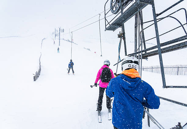 Glenshee, Scotland - A rear view of people using a ski lift at Glenshee resort in the Scottish Highlands duing heavy snowfall.