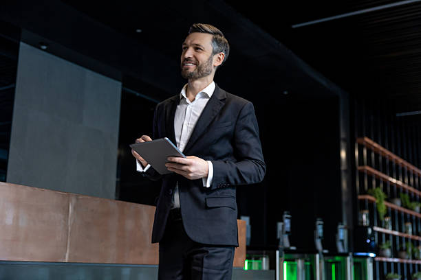 istock Caucasian man at the reception standing with a tablet in hands and looking confident 2230972745