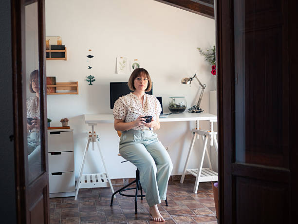istock Artist woman sitting in home studio while holding analog camera in hands with a relaxed expression 2230973321