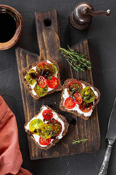 istock Italian bruschetta with ricotta, cherry tomatoes and balsamic sauce on a cutting board and black background top view vertical photo 2230976121