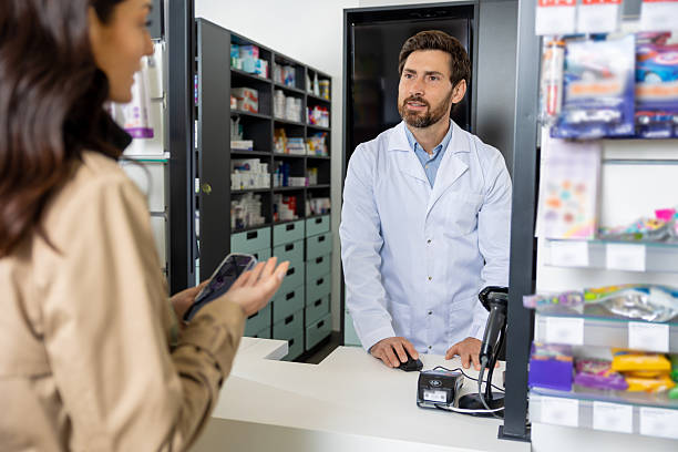 istock Male pharmacist offering pills to a female client 2230977329