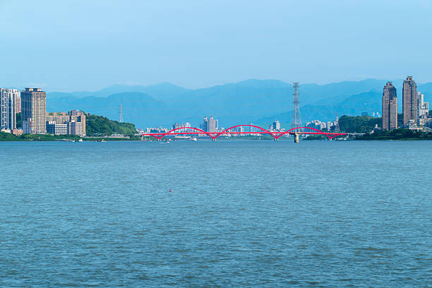 Stunning view of the pink bridge spanning the Danshui River in Taiwan at twilight, with calm waters and distant mountains. Shot on April 29, 2025.