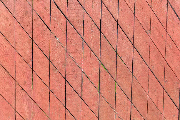 A red fence with a pattern of wood slats. The slats are arranged in a diamond shape