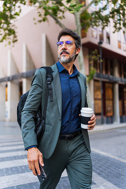 istock Confident businessman walking with coffee and phone in hand 2230979289