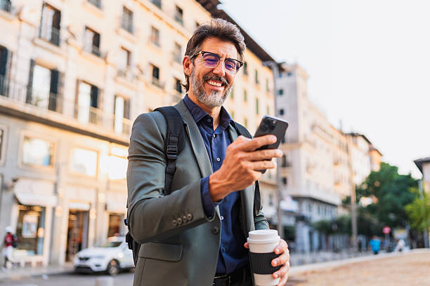 Smiling businessman checking phone while walking outdoors